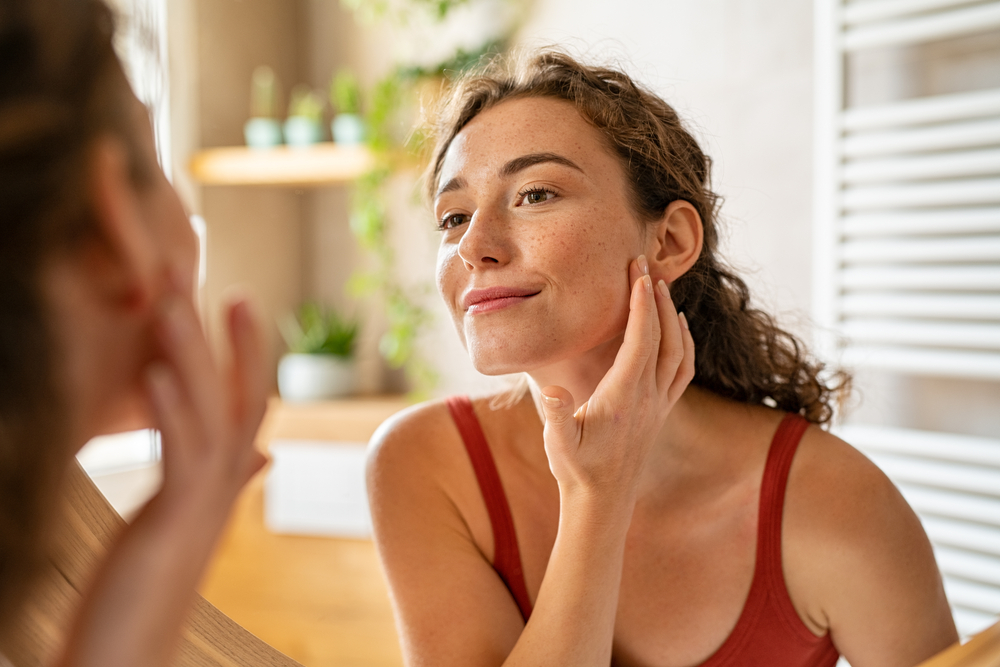 young woman looking at face in mirror