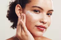 woman putting acne cream on face