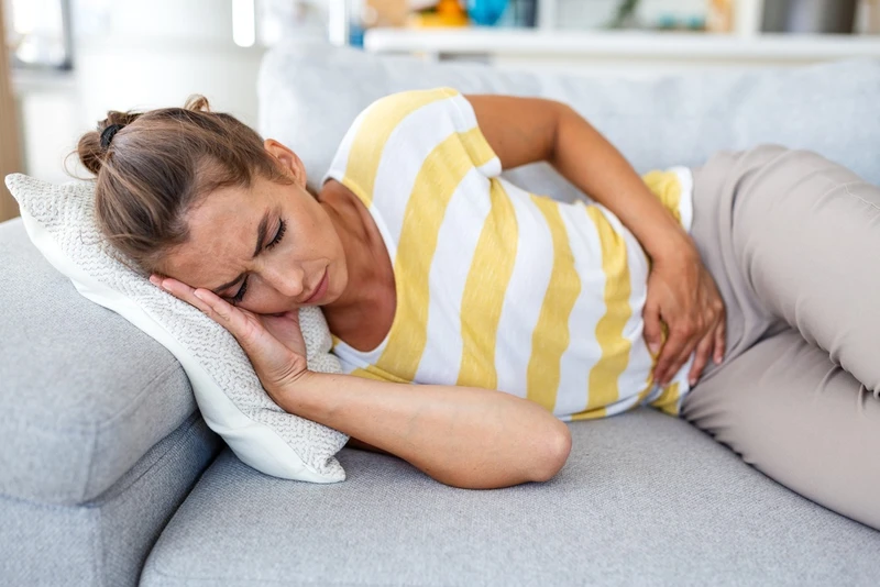 woman laying on couch with bloating